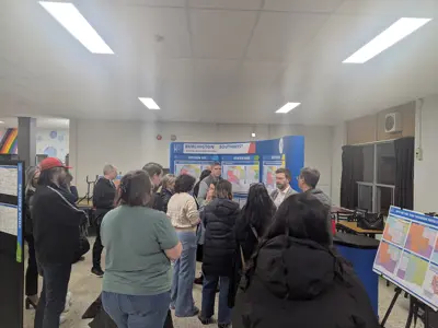 Parents and community members gather around display boards reviewing maps and information during the Burlington Southwest School Boundary Review meeting.