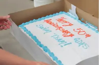 a close up of a cake that says "Happy 50th Anniversary GDHS Swim Team!"