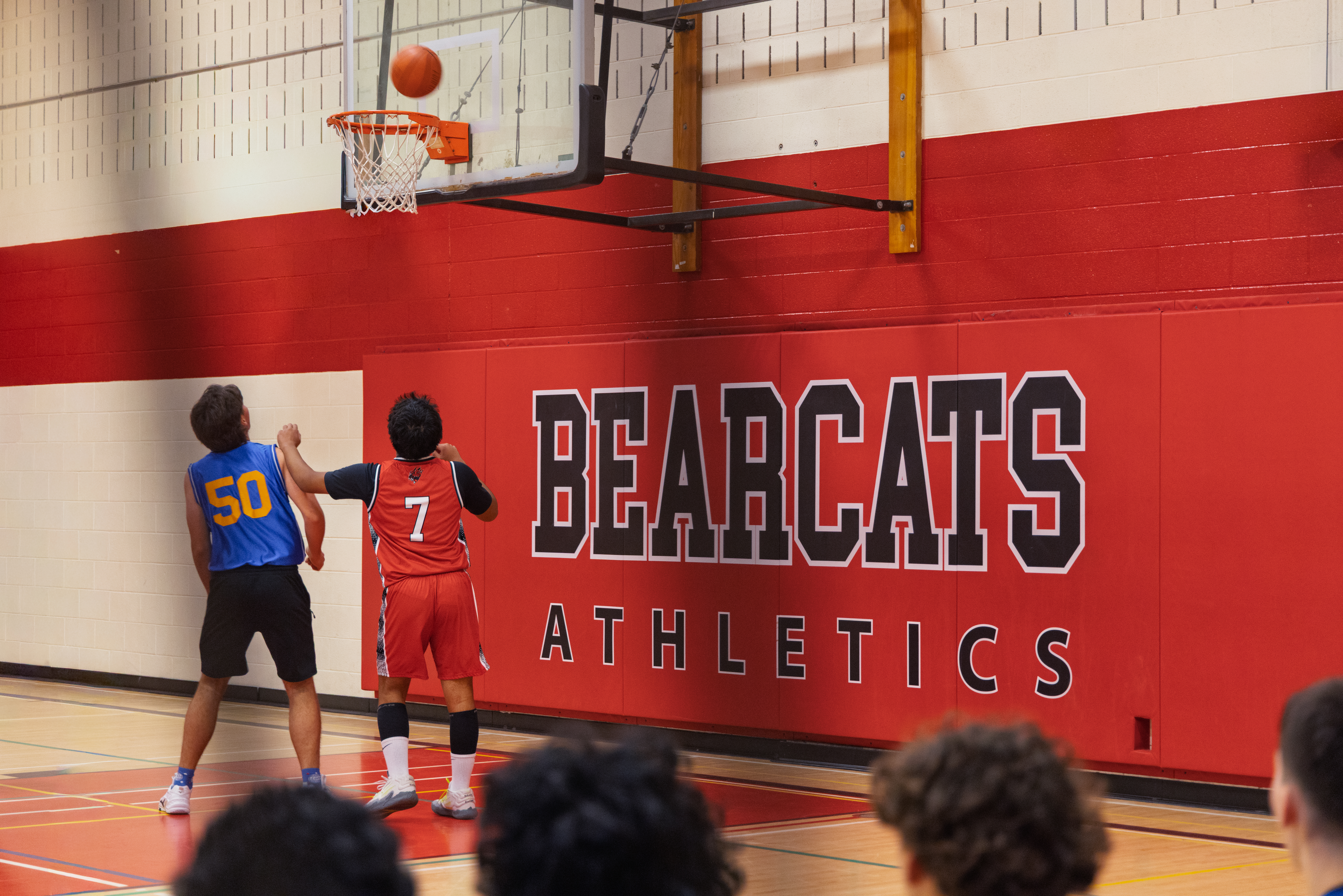 Two students competing in a basketball game beneath the hoop in the Acton Bearcats gym.