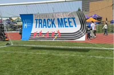 a soccer net on an outdoor field that has a large banner in it that reads "Special Athletics Track Meet"