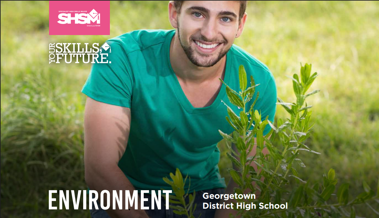 a man posing behind a plant outside.