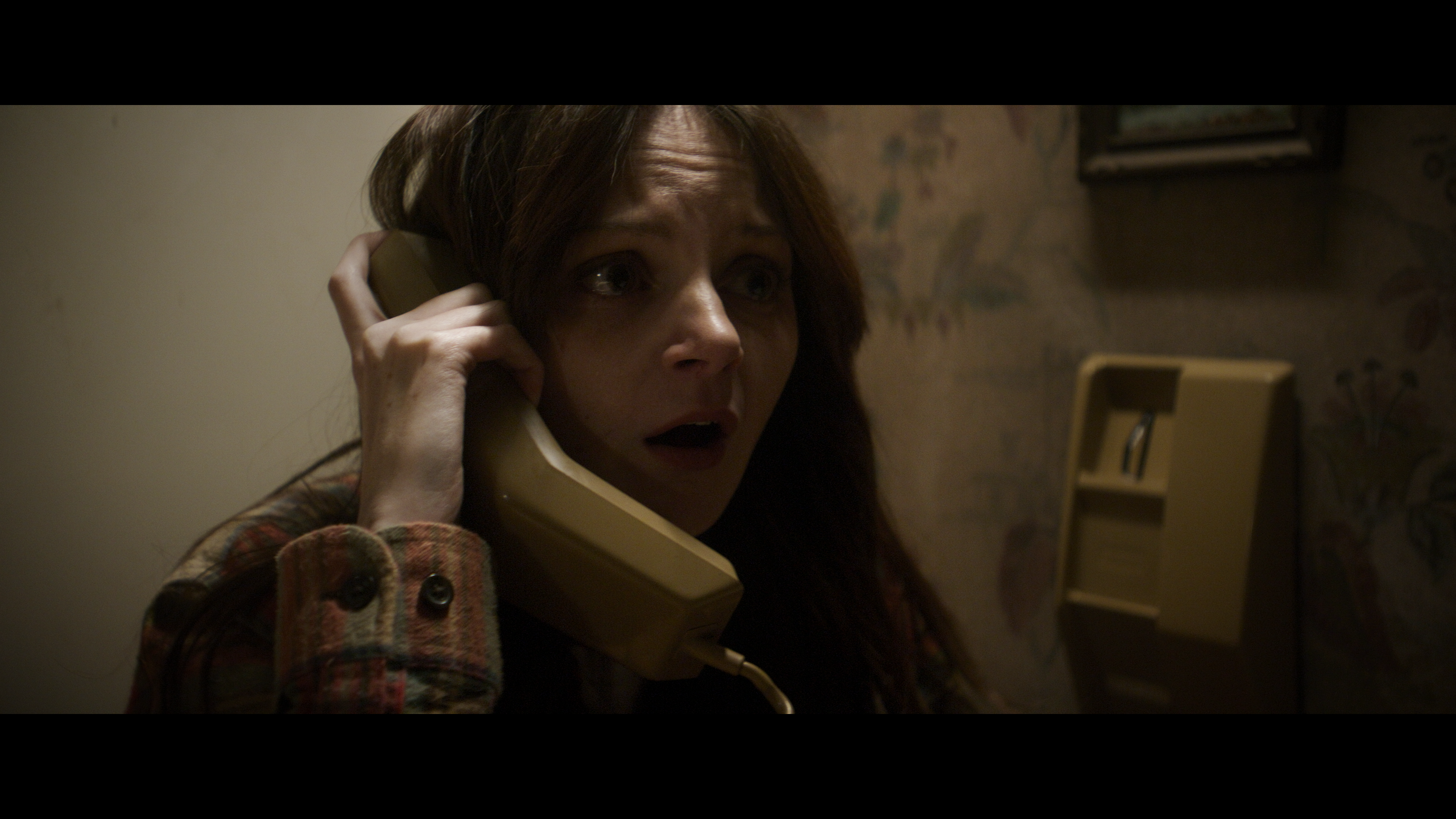 a woman talking on a landline phone in a movie.