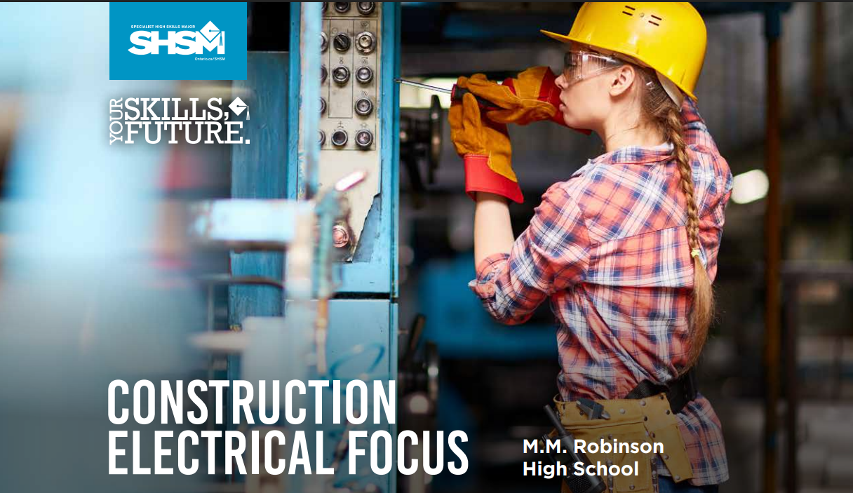 a woman wearing a yellow hard hat, gloves, and protective goggles working in a workshop.