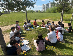 Students learning outside sitting on the grass