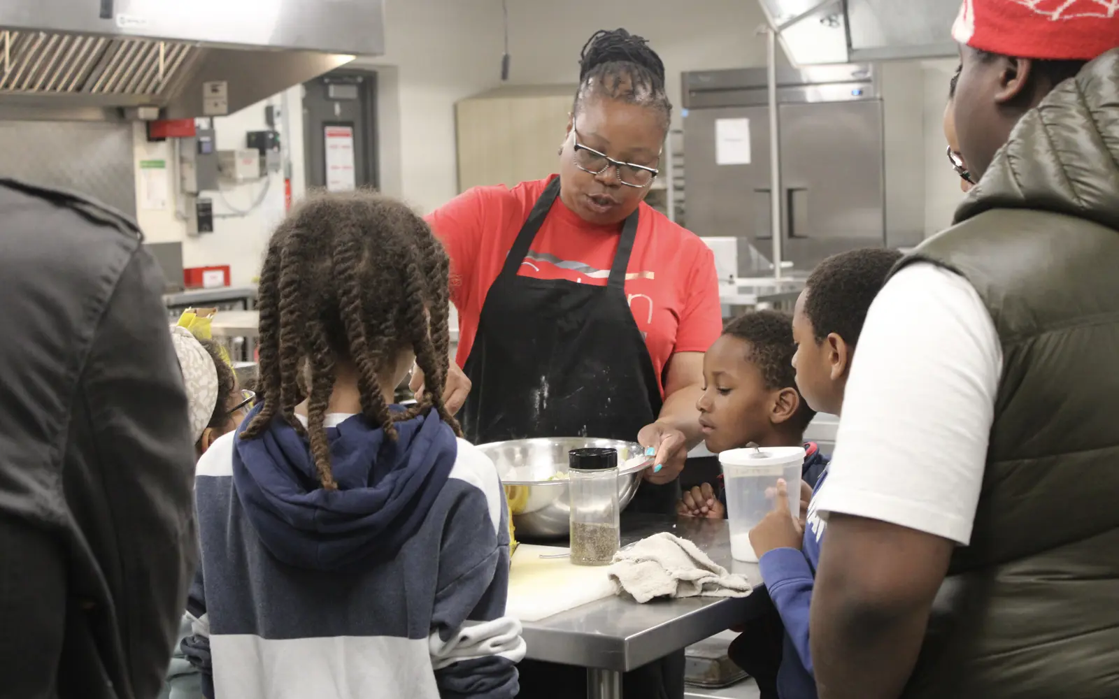 A teacher leads a hands-on Caribbean cooking lesson for students at M.M. Robinson High School's Evening of Black Excellence