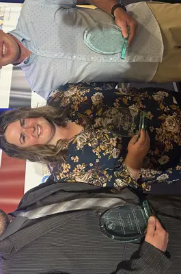 three adults posing side by side holding up glass awards