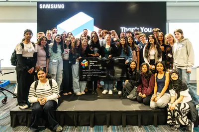 a large group of students posing together, holding a big check in the middle.