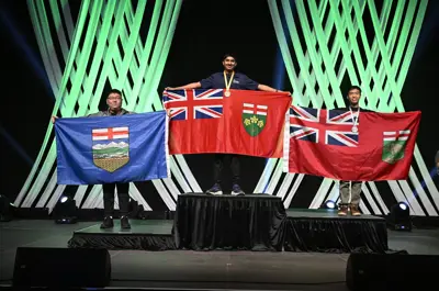 three students on a podium holding up provincial flags of Canada.