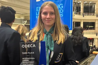 a teenage girl holding up an award. 