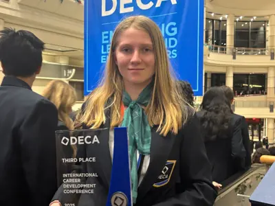a teenage girl holding up an award. 