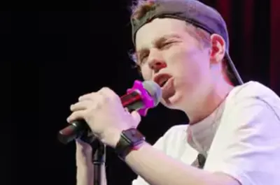 close up of a teenage boy singing into a microphone. 